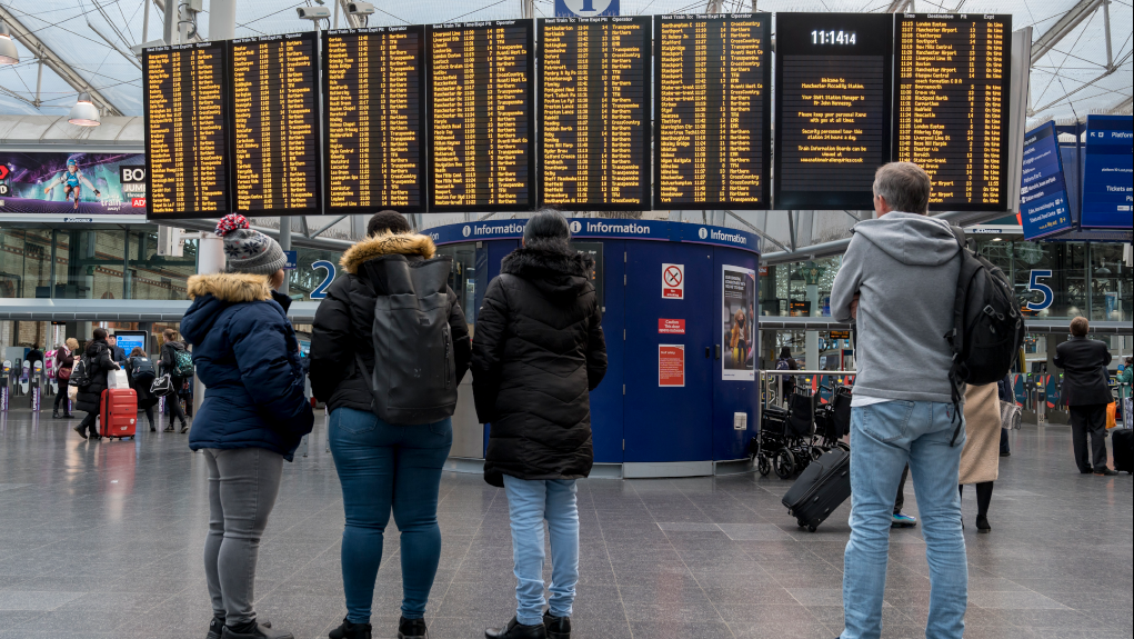 Passengers looking at digital information board at Manchester Piccadilly Station