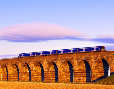 Old masonry arched viaduct carrying a train near Edinburgh, Scotland with sunset lighting