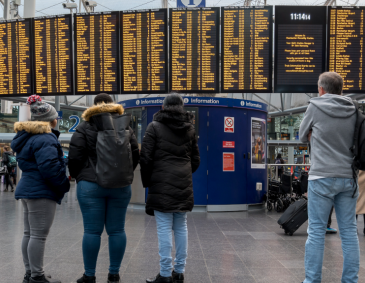 Passengers looking at digital information board at Manchester Piccadilly Station